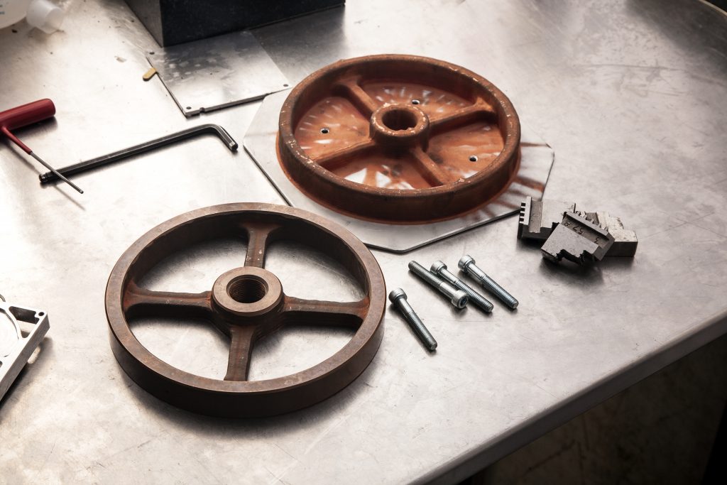 制造零件-铜皮带轮24分钟制造。图像显示一个后加工滑轮和一个打印。通过Spee3D照片。