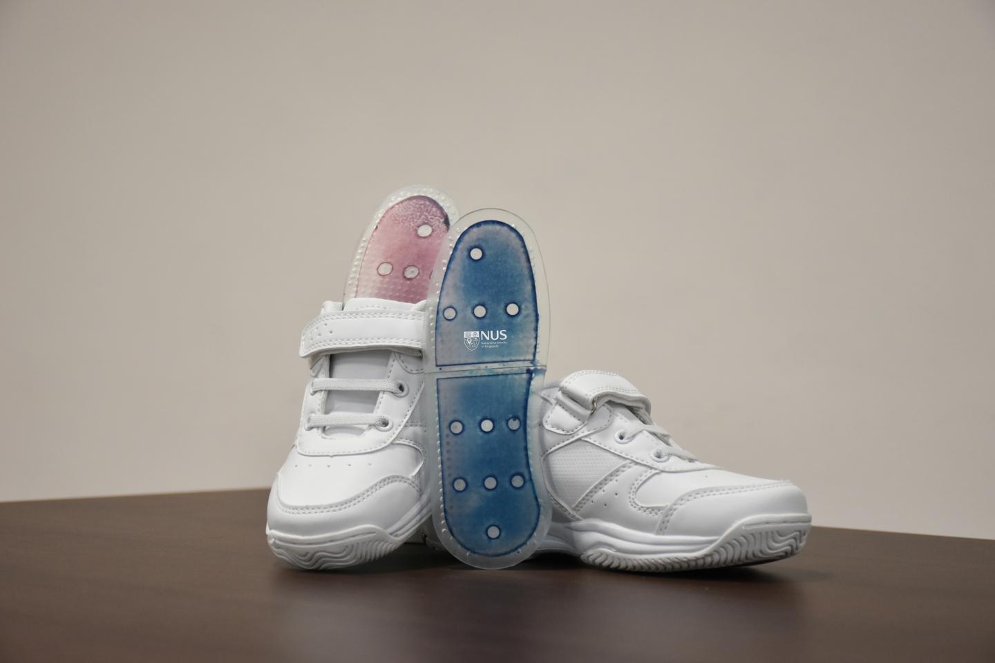 鞋底原型涂有新的薄膜，因为它吸收了水分，从而从蓝色变为粉红色。图像通过nus。